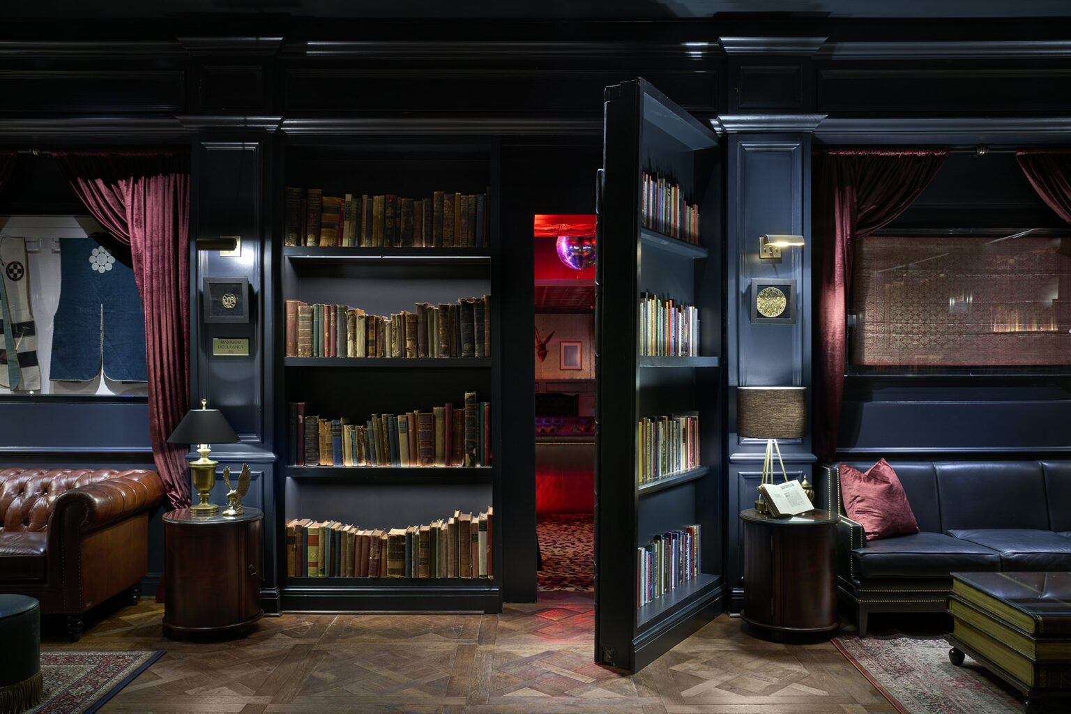Babou's speakeasy at Hôtel Swexan, featuring a paneled room with a concealed bookcase door opening to a red-lit inner room — a deliberately designed destination that guests seek out and return to.